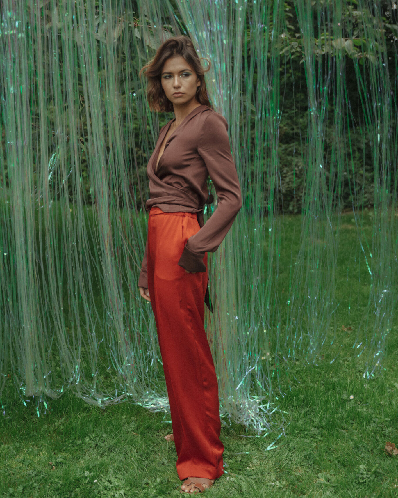 girl posing in orange pants and brown silk top