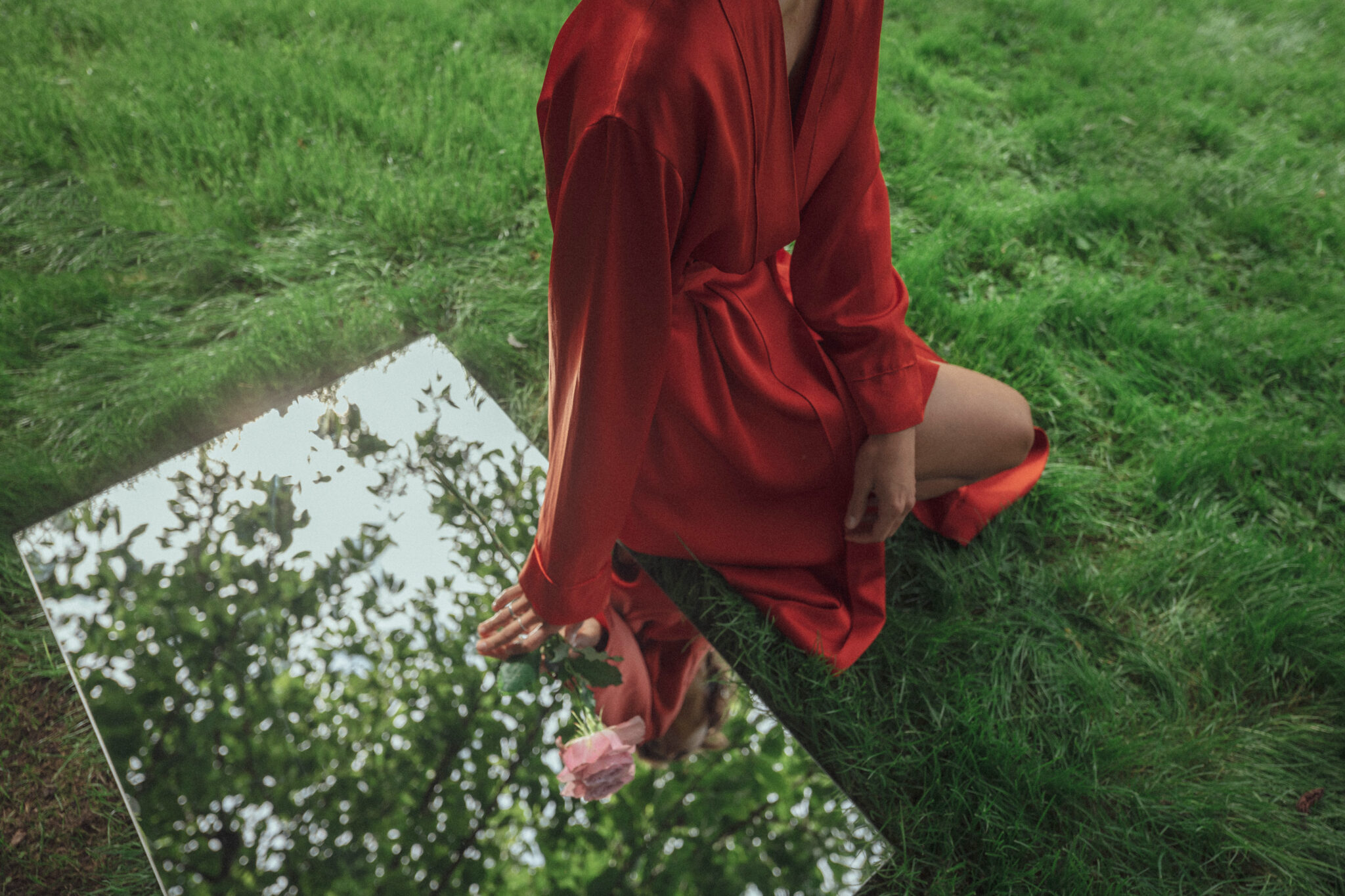 Girl laying on mirror in an orange robe in grass